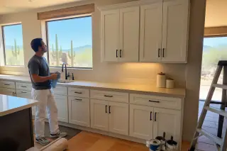 Contractor wiping down freshly refinished kitchen cabinets in a Phoenix, AZ home with a desert view.