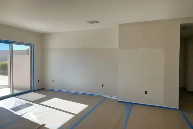 Freshly repaired and painted walls in an empty living room during a drywall project in Phoenix, AZ.