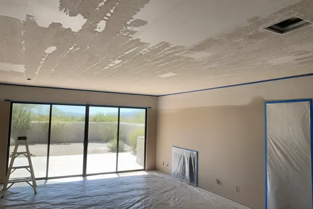 Popcorn ceiling removal in progress in an empty residential living room in Phoenix, AZ.