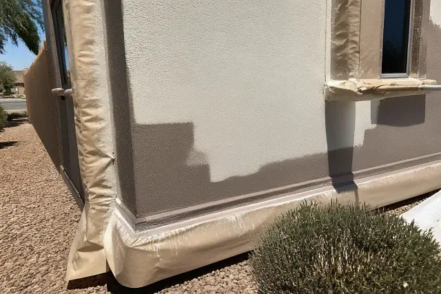 Exterior stucco wall with protective masking and wet paint marks during a commercial painting project in Gilbert, AZ.