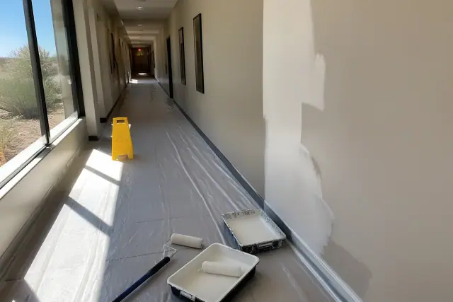 Commercial painting progress in a professional building hallway with supplies and floor protection in Surprise, AZ.