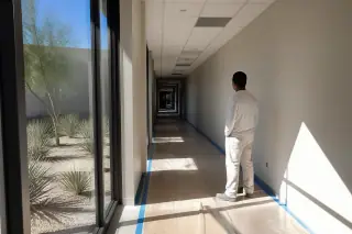 Technician reviewing a freshly painted hallway with bright sunlight in a Phoenix, AZ office building.