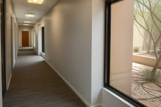 Freshly painted office hallway with uniform satin walls and a view of desert landscaping in Phoenix, AZ.