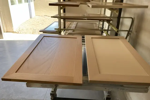 Oak and MDF cabinet door samples on drying racks in a Phoenix, AZ workshop.