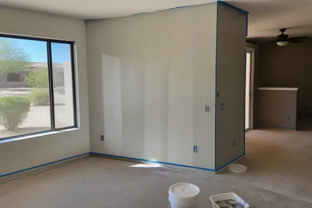 Empty apartment living room with fresh wall paint and painter's tape on baseboards in Phoenix, AZ.