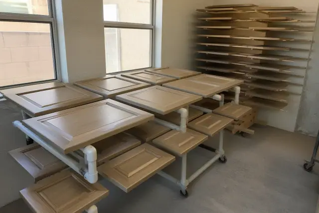 Dismantled cabinet doors and drawers on drying racks inside a workshop in Phoenix, AZ.