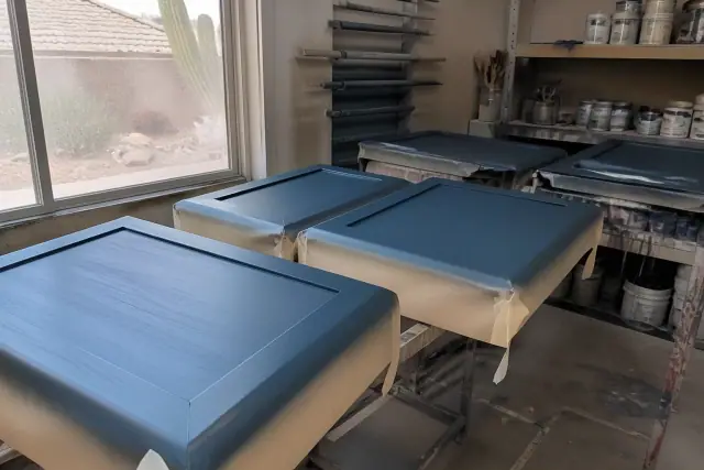 Paint cans and masked kitchen cabinets in a Phoenix, AZ workshop during a refinishing project.