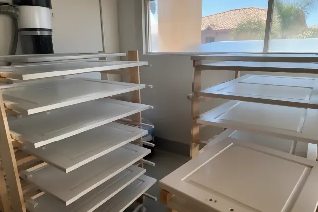 Dismantled kitchen cabinet doors drying on racks during a cabinet refinishing project in Phoenix, AZ.