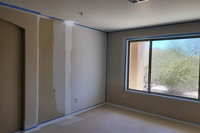 Drywall repair and fresh paint on living room walls in a Mesa, AZ home with desert views through the window.