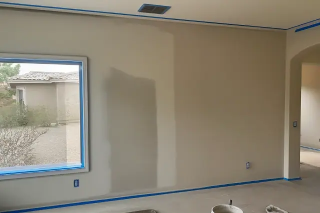 Drywall patch and fresh paint on a residential wall in Goodyear, AZ, with desert scenery visible through the window.
