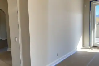 Freshly painted living room wall with a blended drywall patch and taped trim in a Phoenix, AZ home.