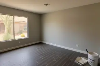 Finished living room walls with a paint tray and bucket visible near a window in a Phoenix, AZ home.