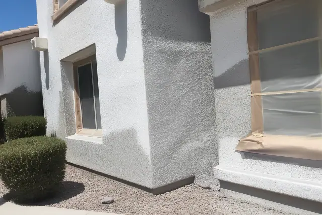 A work-in-progress elastomeric stucco wall on a building in Phoenix, AZ, with protective paper near the window frame.