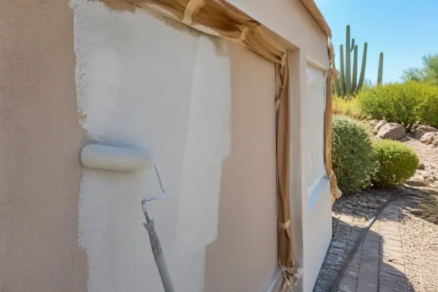 A painter applying fresh paint to a stucco wall at a home jobsite in Paradise Valley, AZ.