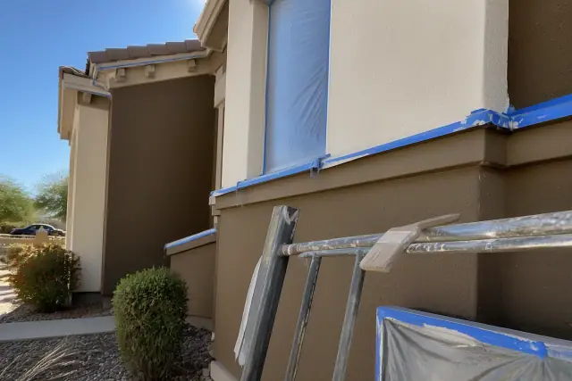 A contractor documenting exterior painting on a multi-story stucco home with desert landscaping in Chandler, AZ.