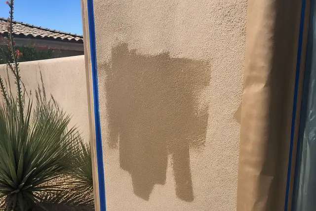 Freshly painted stucco wall with blue painter's tape and desert landscaping in Paradise Valley, AZ.