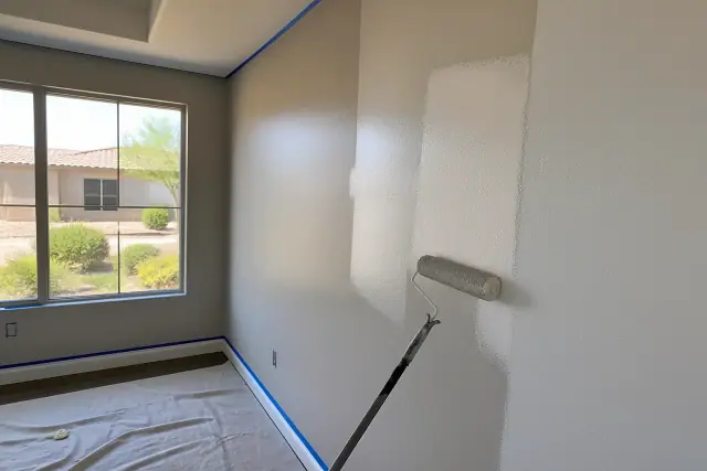 Freshly painted wall with painter's tape in a Gilbert, AZ home with a view of desert landscaping through the window.