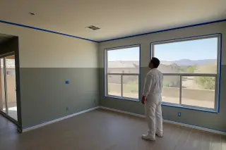 Empty living room with taped trim and fresh paint showing color transition in a Phoenix, AZ home.