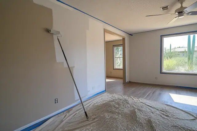 Living room during popcorn ceiling removal and painting with a paint roller and scraped debris in Phoenix, AZ.