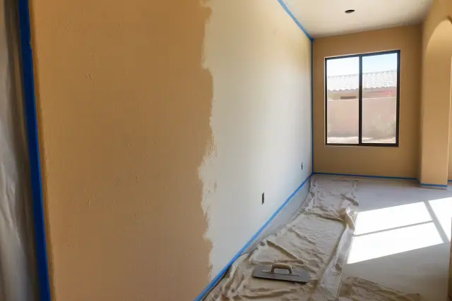 Freshly painted stucco wall with a trowel on a drop cloth in a residential living space in Phoenix, AZ.