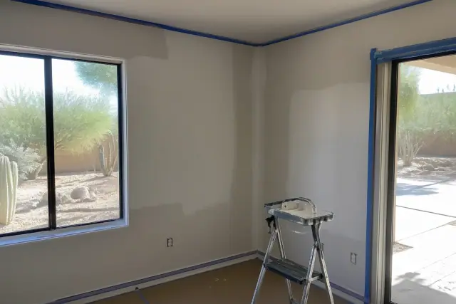 Technician applying joint compound to a corner seam in a residential living room in Phoenix, AZ.