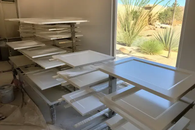 Dismantled kitchen cabinet doors drying on racks in a workshop in Phoenix, AZ.