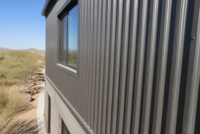 Newly painted metal siding on a multi-story building under harsh sunlight in Phoenix, AZ.