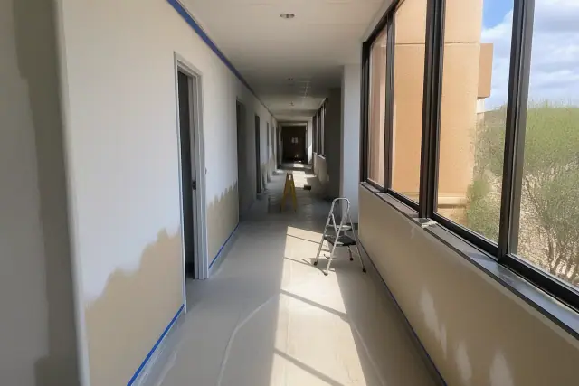 Half-painted office corridor with masking tape and floor protection during a commercial renovation in Phoenix, AZ.