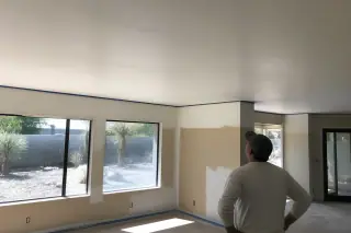Site manager inspecting a smooth ceiling after popcorn removal in a Phoenix, AZ home.