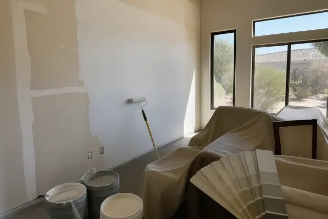 Open paint buckets, rollers, and color swatches against a wall transition during a painting project in Phoenix, AZ.