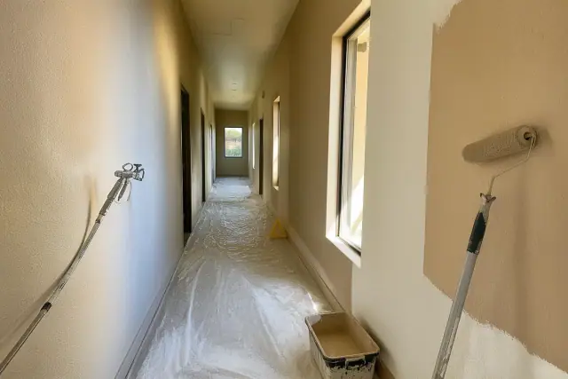 Commercial painting in progress in a long office corridor with paint rollers and supplies in Phoenix, AZ.