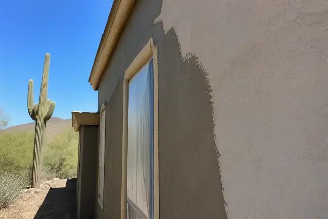 Freshly applied stucco wall with protective masking near a window at a job site in Paradise Valley, AZ.