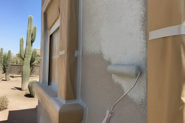 Stucco wall with masking paper during a painting project in Tempe, AZ, featuring saguaro cacti in the background.