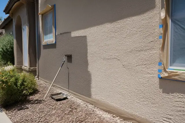 Applying textured acrylic coating to a stucco wall during a home painting project in Peoria, AZ.