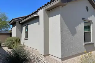 Freshly painted residential stucco wall with desert xeriscaping under bright sunlight in Phoenix, AZ.