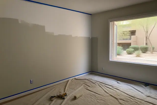Empty apartment living room with fresh paint and taped trim, overlooking desert landscaping in Phoenix, AZ.