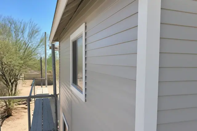 Vinyl siding installation on a building with corner posts and window trim in Phoenix, AZ.