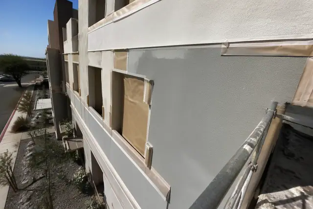 Commercial building repainting in progress with masking tape on stucco walls in Phoenix, AZ.