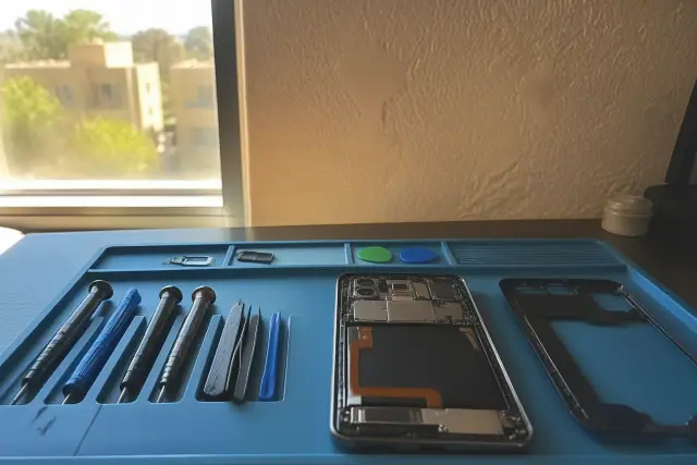 An open Android tablet with internal components and repair tools on a workstation in Avondale, AZ.