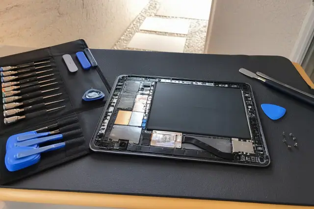 An open tablet being repaired with professional tools on a workstation at a jobsite in Peoria, AZ.