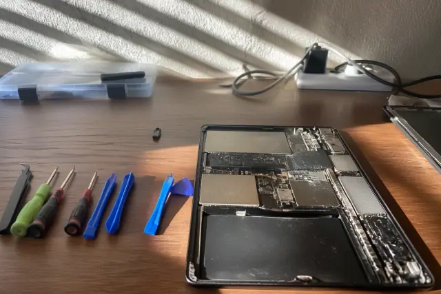 Repairing an open tablet with professional tools on a workbench in Phoenix, AZ.