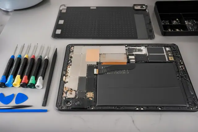 An opened smartphone with internal components on an organized repair workstation in Gilbert, AZ.