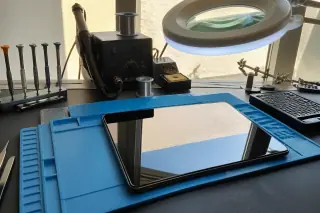 Completed Android tablet on a workbench with a soldering station and tools in Phoenix, AZ.