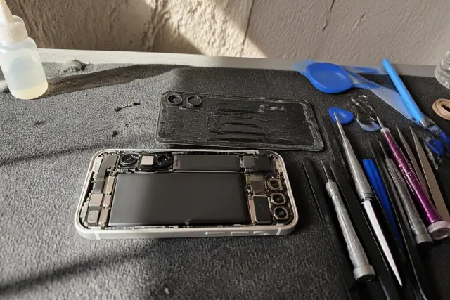 Opened smartphone with exposed internal components during a repair on a workbench in Phoenix, AZ.