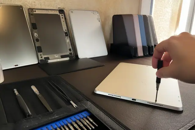 iPad back glass and housing repair on a workbench in Phoenix, AZ.
