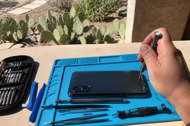 A smartphone photo of a phone back glass repair in progress with precision tools on a workbench in Glendale, AZ.
