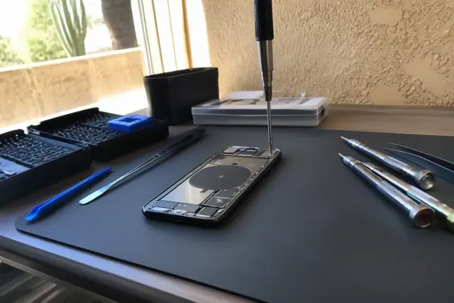 Technician repairing a smartphone back glass on an anti-static mat in a Paradise Valley, AZ workshop.