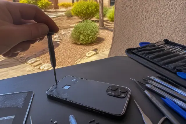 A smartphone repairing a phone's back glass with tools on a desk in Peoria, AZ.