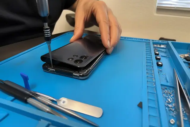 Technician aligning back glass on a smartphone during a repair in an Avondale, AZ workshop.