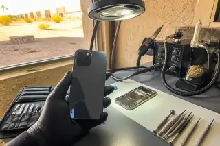 Finished back glass repair on a smartphone at a sunlit workbench in Phoenix, AZ.